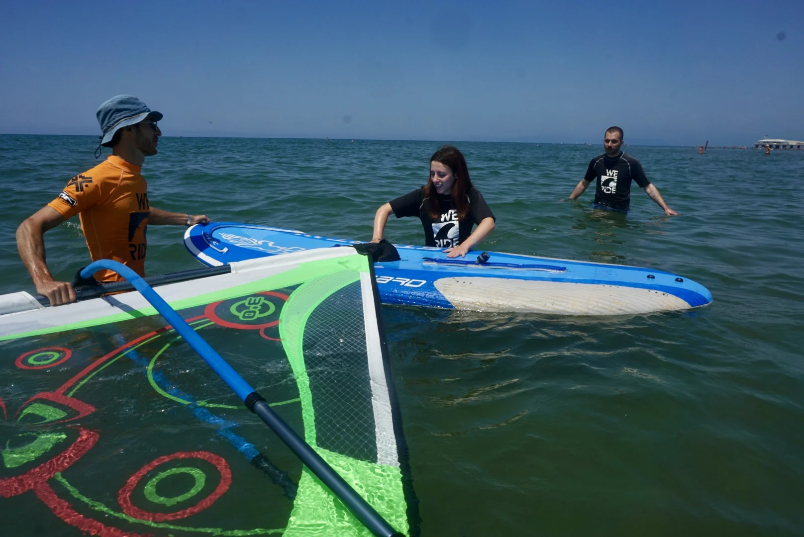 Primi passi in acqua con tavola e vela durante una lezione Windsurf WE RIDE